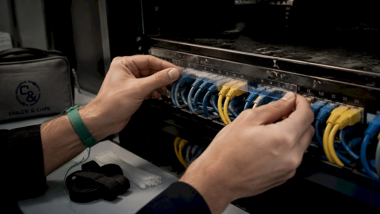 Hands holding wrap-around labels near labeled patch panel