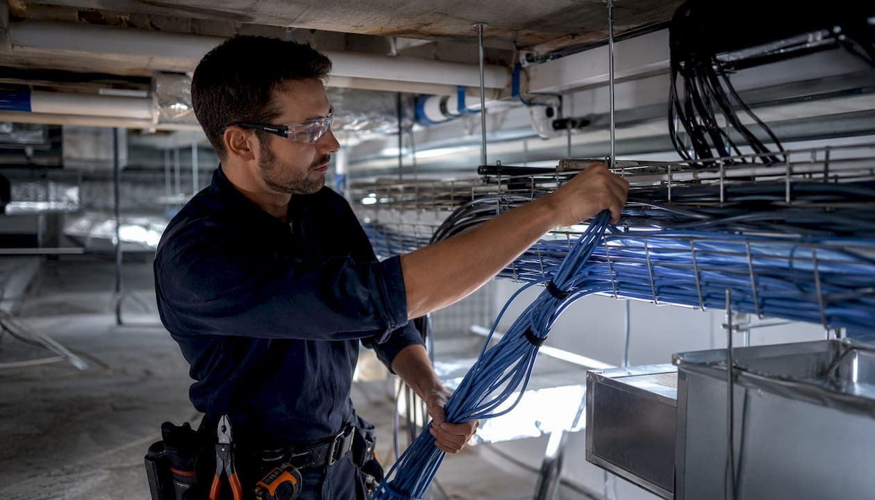 Facilities worker installing horizontal cabling in ceiling plenum