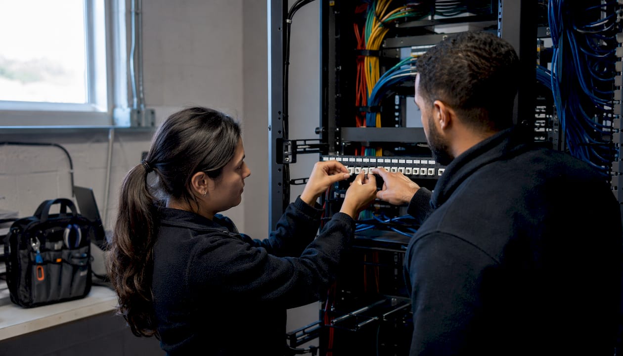 Technicians installing keystone modules in patch panel