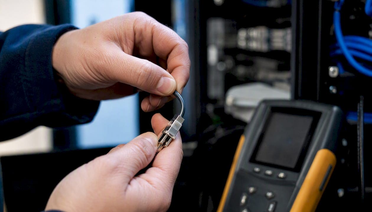 Hands flex-testing cable connector in network closet