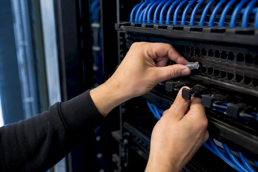 Hands terminating Cat6A cable on patch panel