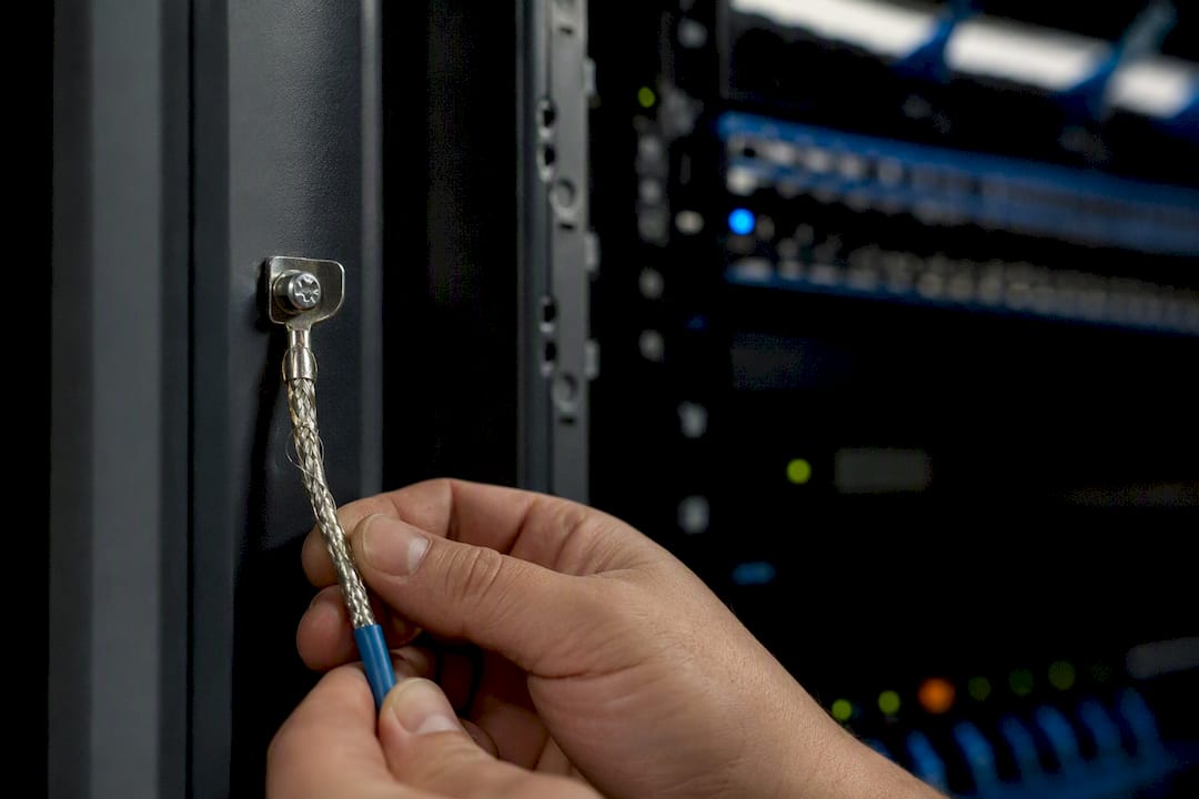Hands connecting cable shield to grounding lug