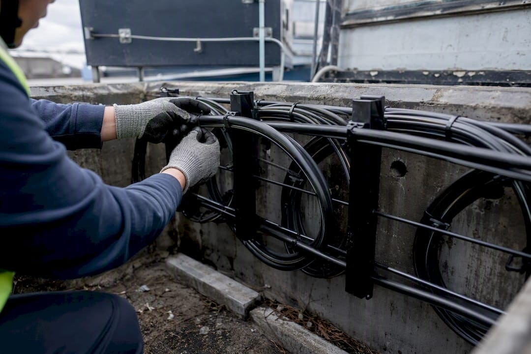 Worker securing fiber slack elevated in outdoor vault