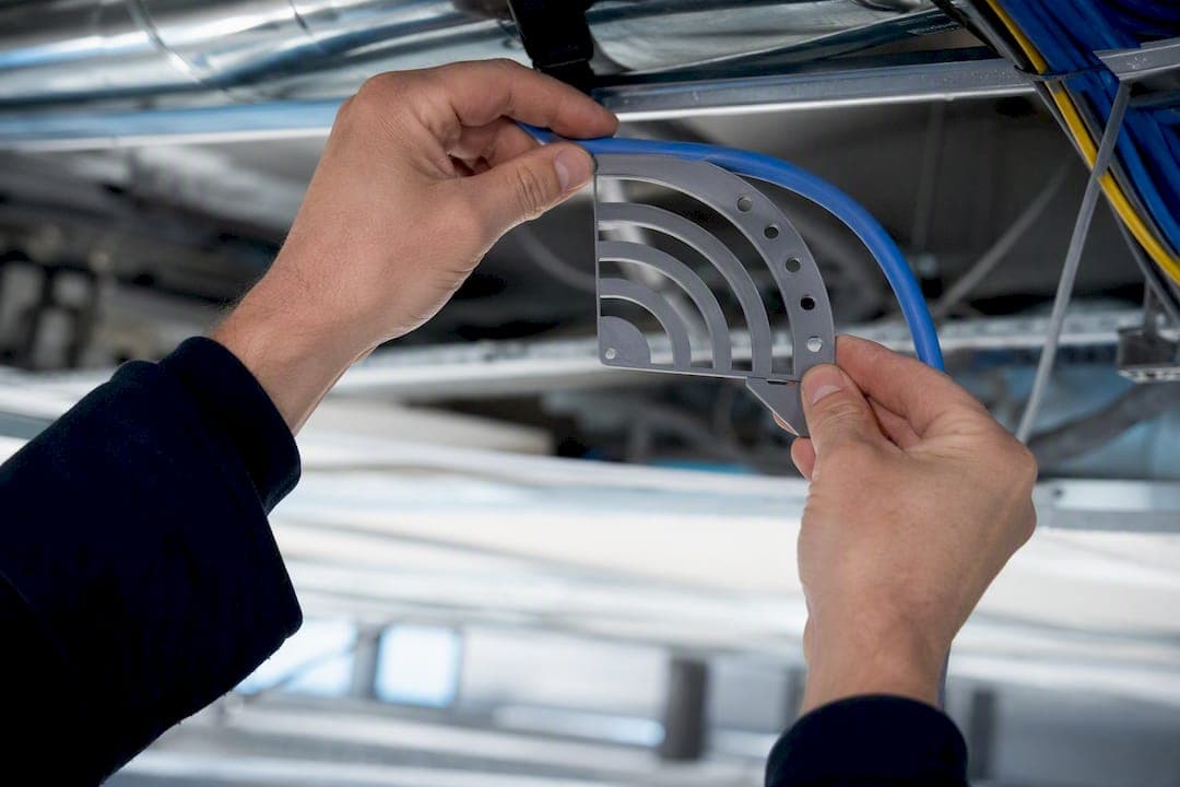 Hands comparing Cat6 cable bend with radius templates